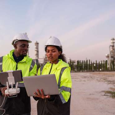 Engineer Specialists Pilot Drone on Construction Site. Architectural Engineer and Safety Engineering Inspector Fly Drone at industrial plant.